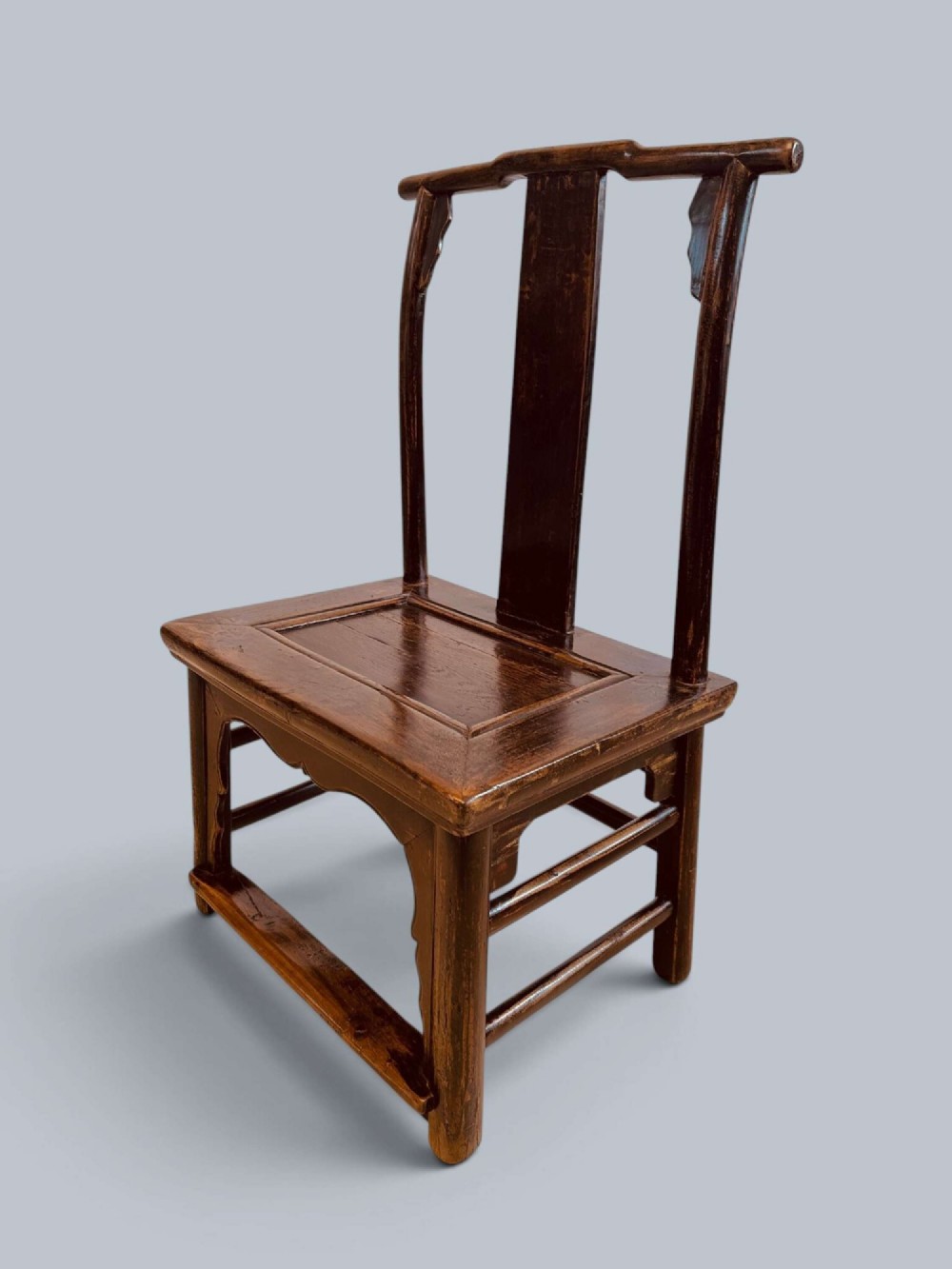 A pair of dark-lacquered antique Chinese childrens chairs with yoke-style top rails and carved aprons. View IV