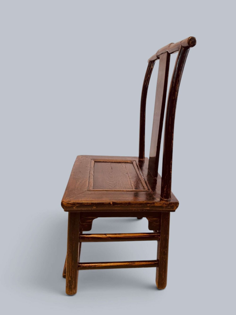 A pair of dark-lacquered antique Chinese childrens chairs with yoke-style top rails and carved aprons. View V