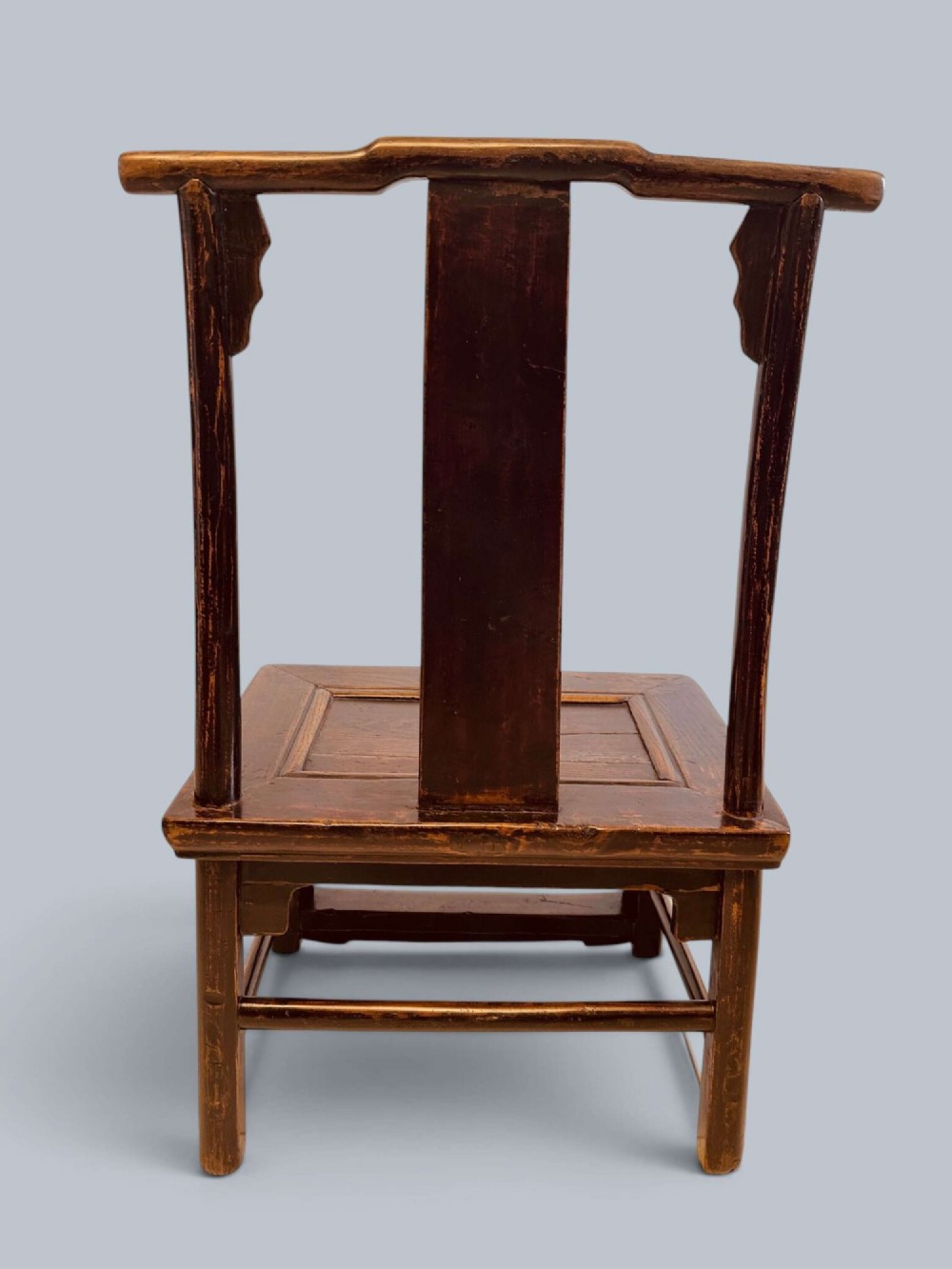 A pair of dark-lacquered antique Chinese childrens chairs with yoke-style top rails and carved aprons. View VI