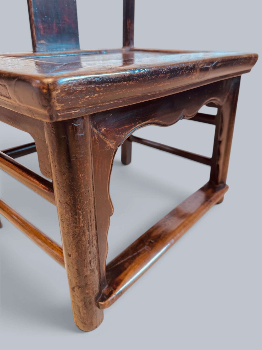 A pair of dark-lacquered antique Chinese childrens chairs with yoke-style top rails and carved aprons. View VII