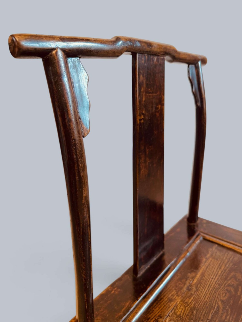 A pair of dark-lacquered antique Chinese childrens chairs with yoke-style top rails and carved aprons. View VIII