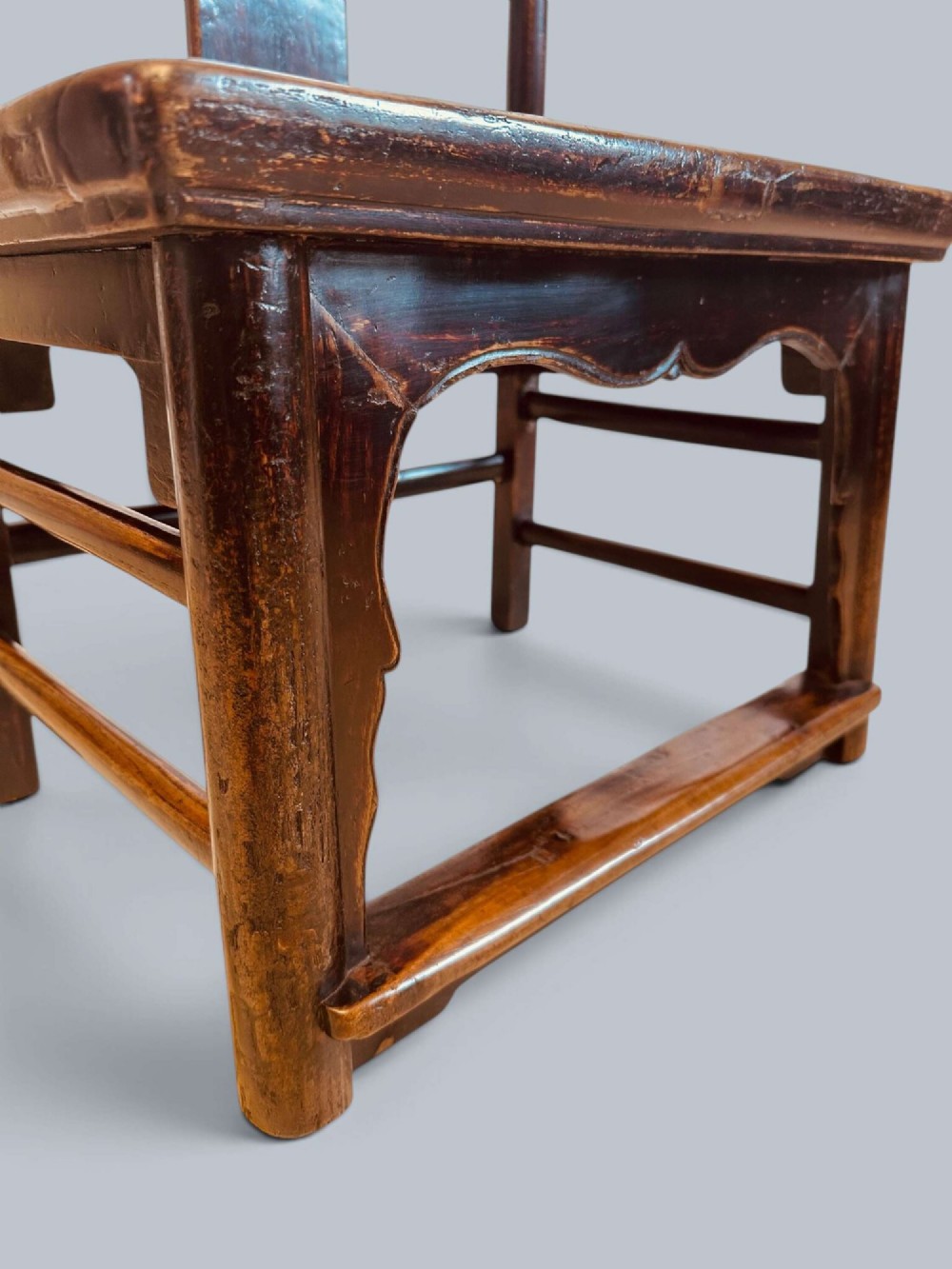 A pair of dark-lacquered antique Chinese childrens chairs with yoke-style top rails and carved aprons. View IX