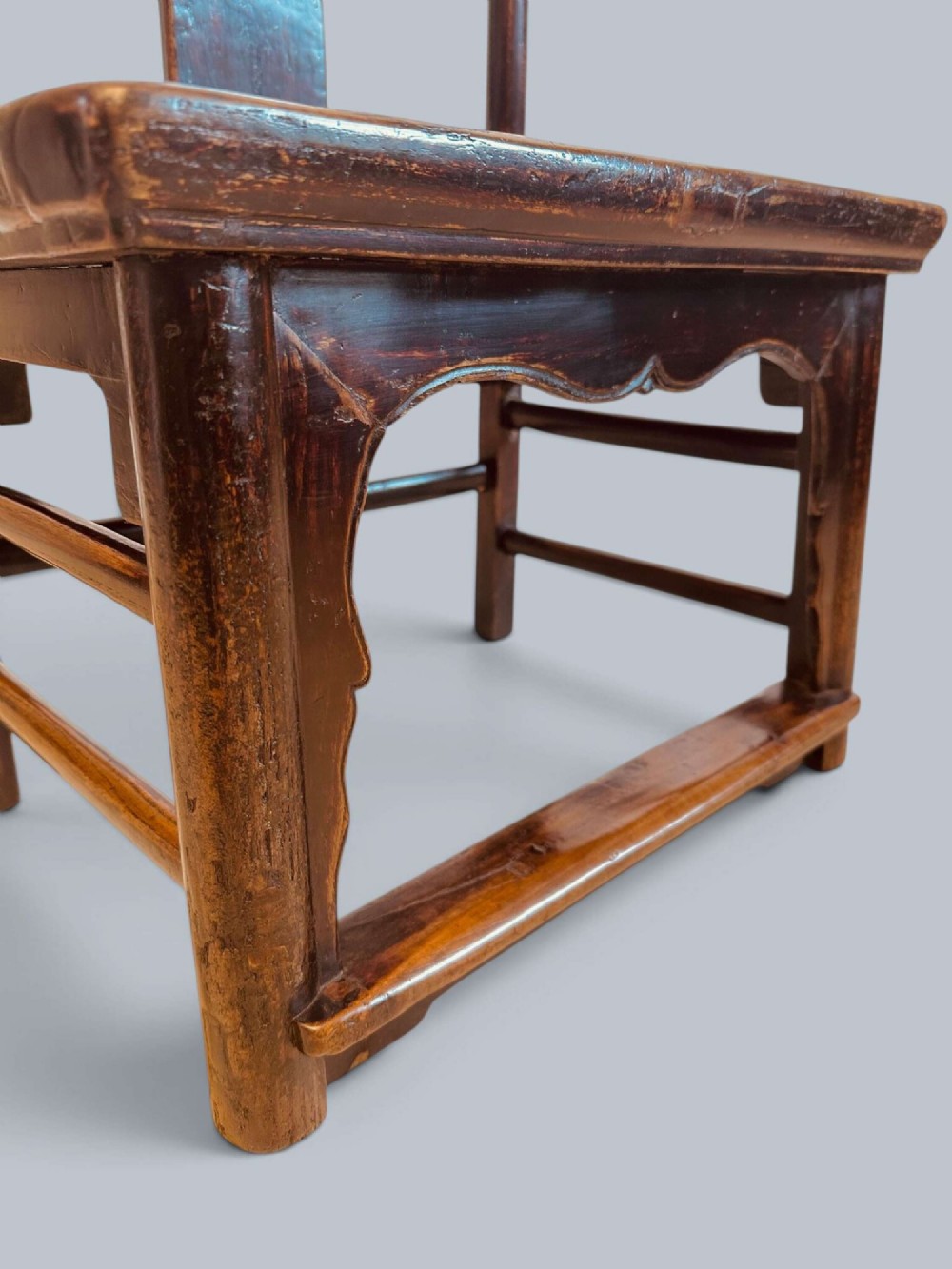 A pair of dark-lacquered antique Chinese childrens chairs with yoke-style top rails and carved aprons. View X