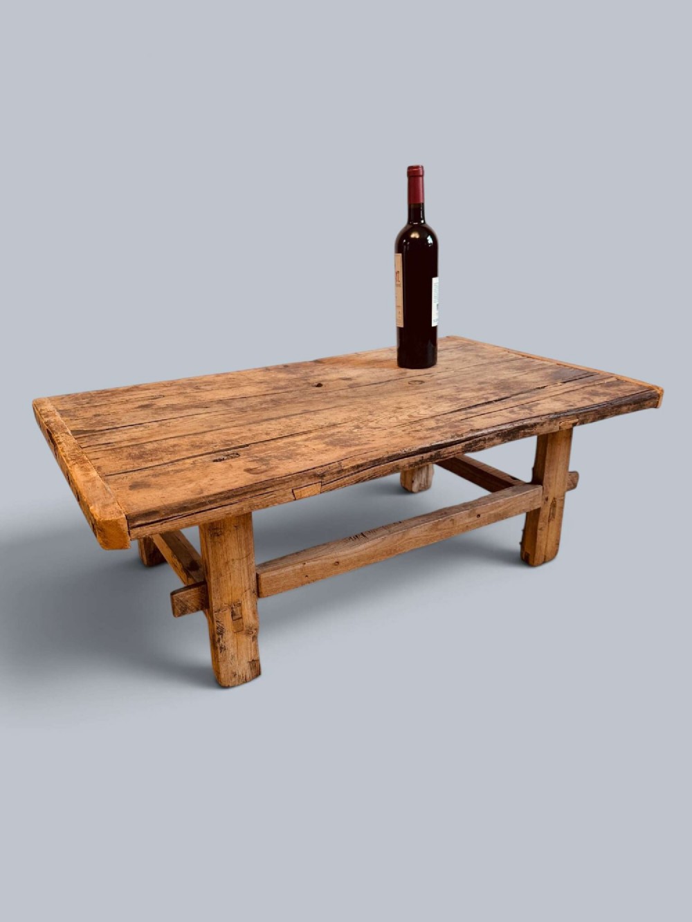 A low rustic pine market table featuring thick block legs, exposed mortise and tenon joinery, and a weathered wood top.