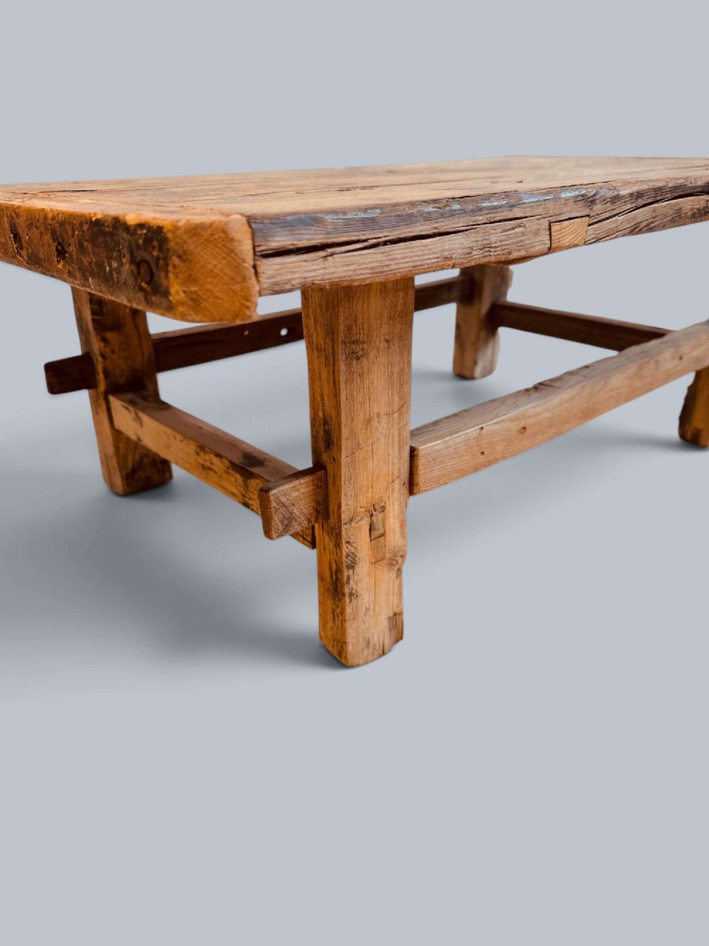 A low rustic pine market table featuring thick block legs, exposed mortise and tenon joinery, and a weathered wood top. View III
