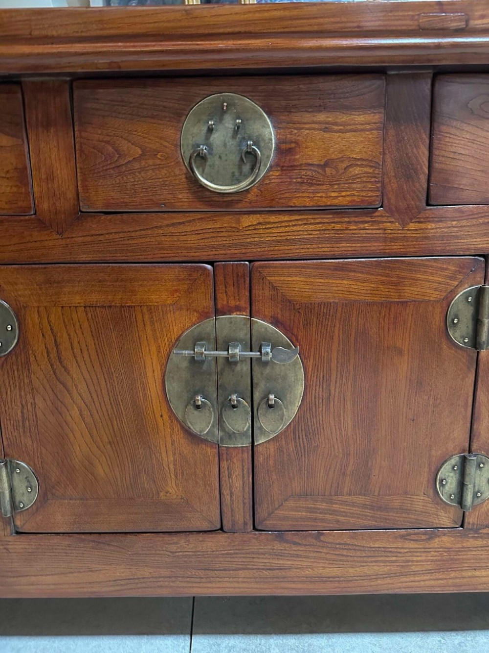 A warm brown Chinese elm altar cabinet featuring three upper drawers, two central cupboard doors, and round brass hardware. View II