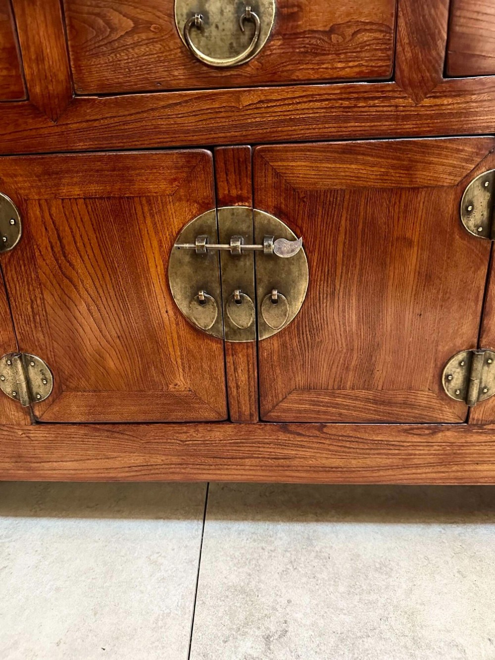 A warm brown Chinese elm altar cabinet featuring three upper drawers, two central cupboard doors, and round brass hardware. View XII