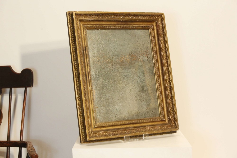 A 19th-century French rectangular giltwood wall mirror featuring a moulded frame with detailed borders and a heavily foxed glass plate.