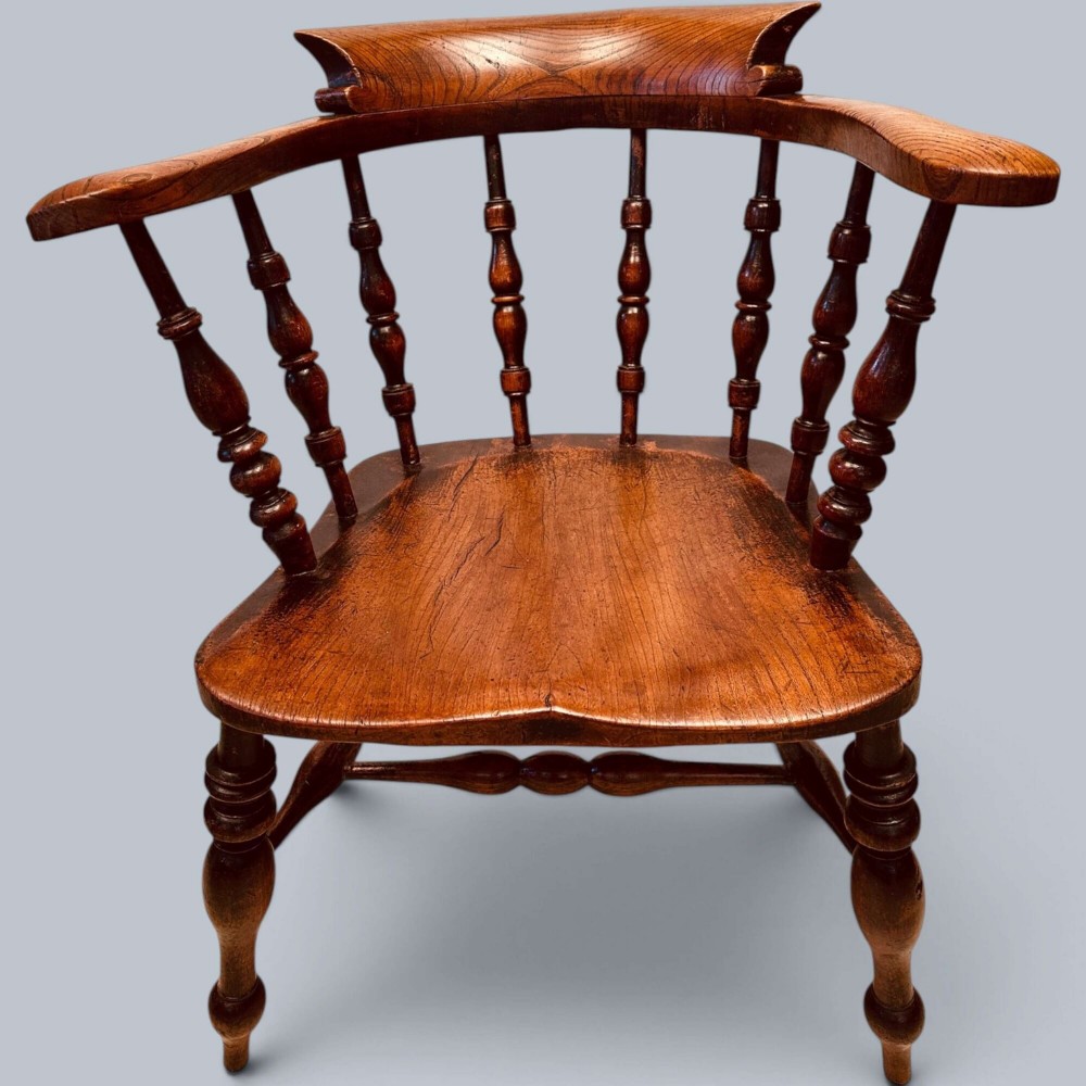 A near pair of warm brown antique elm Windsor captains chairs with turned spindles and curved armrests. View II