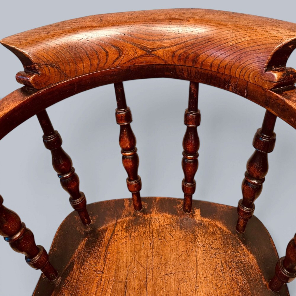 A near pair of warm brown antique elm Windsor captains chairs with turned spindles and curved armrests. View III