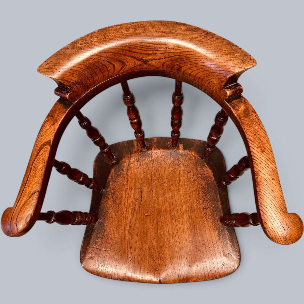 A near pair of warm brown antique elm Windsor captains chairs with turned spindles and curved armrests. View IV
