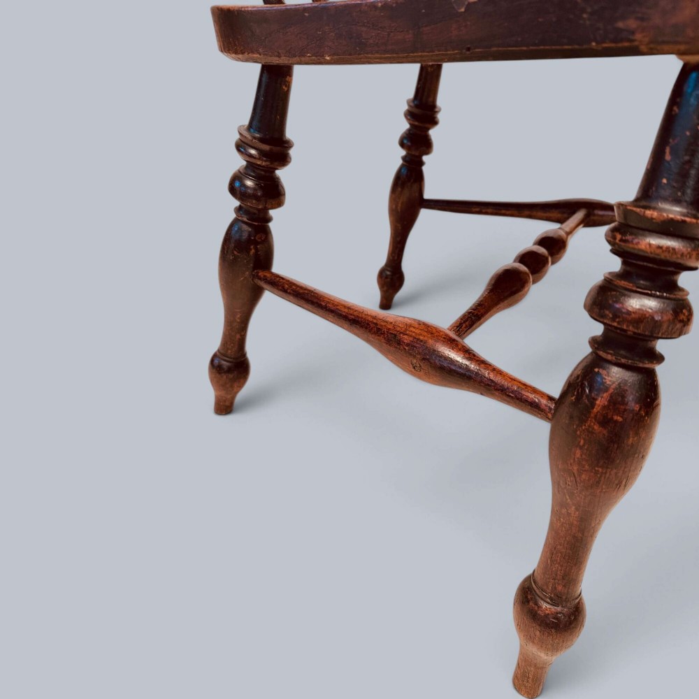 A near pair of warm brown antique elm Windsor captains chairs with turned spindles and curved armrests. View VI