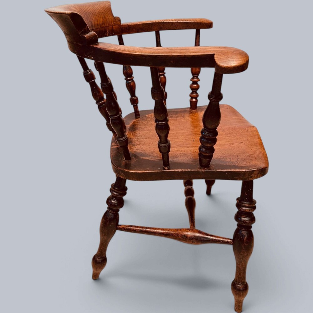 A near pair of warm brown antique elm Windsor captains chairs with turned spindles and curved armrests. View VII