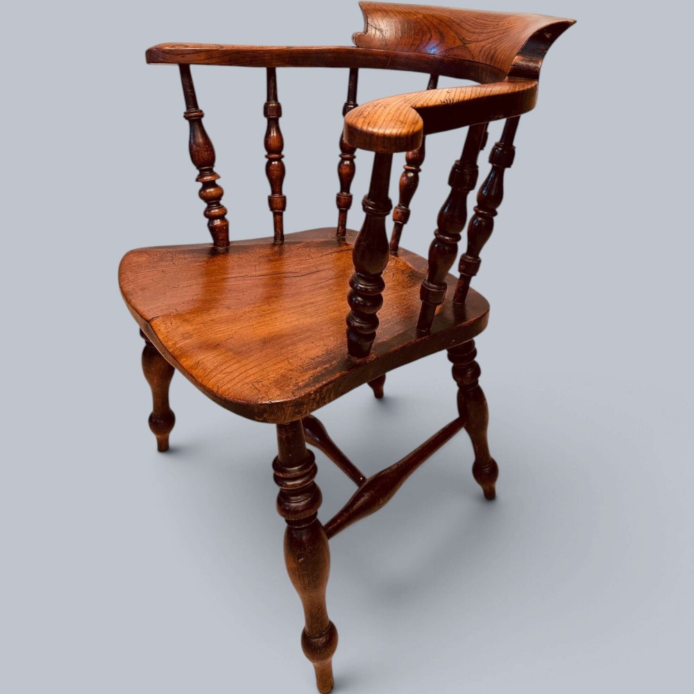A near pair of warm brown antique elm Windsor captains chairs with turned spindles and curved armrests. View VIII