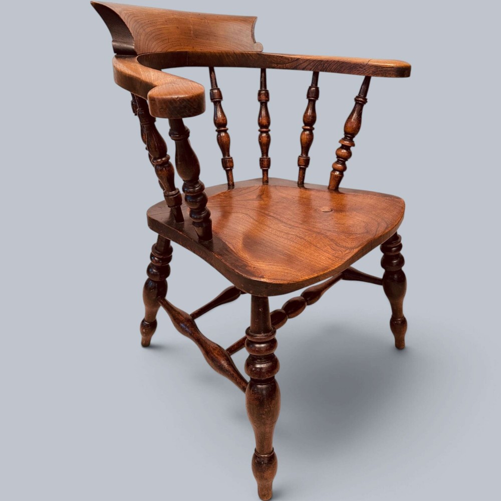 A near pair of warm brown antique elm Windsor captains chairs with turned spindles and curved armrests. View IX