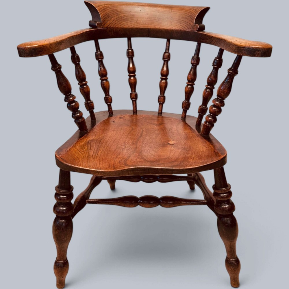 A near pair of warm brown antique elm Windsor captains chairs with turned spindles and curved armrests. View X