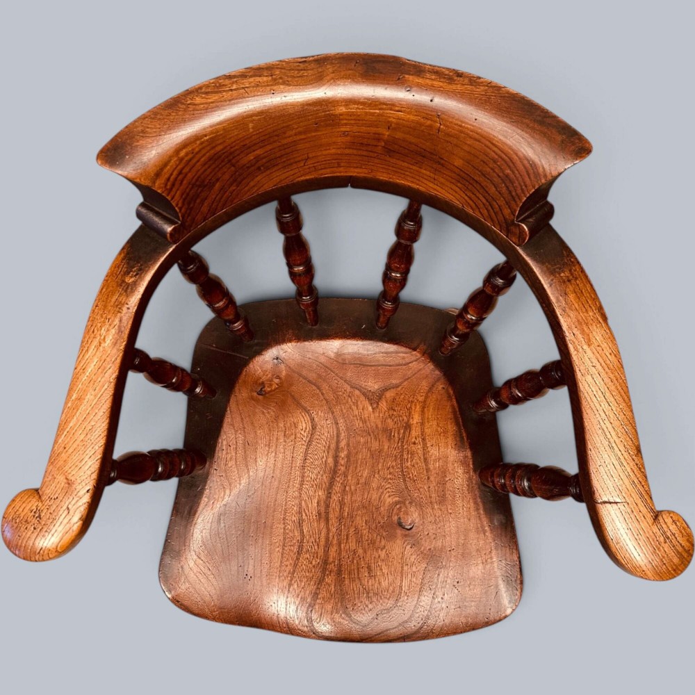 A near pair of warm brown antique elm Windsor captains chairs with turned spindles and curved armrests. View XI