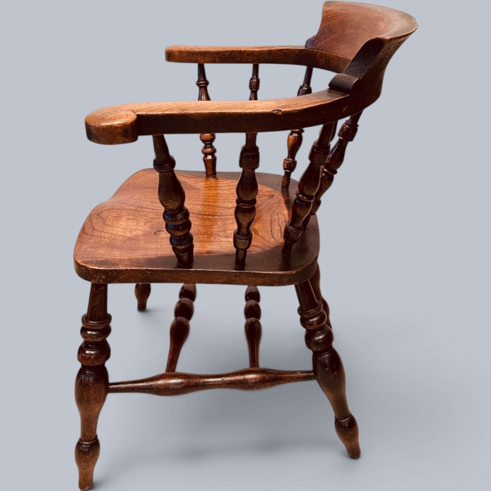 A near pair of warm brown antique elm Windsor captains chairs with turned spindles and curved armrests. View XII