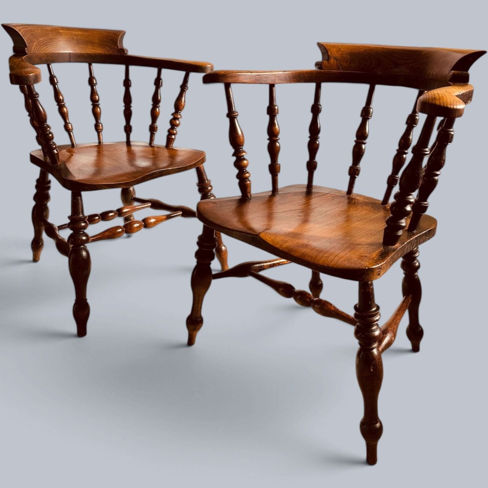A near pair of warm brown antique elm Windsor captains chairs with turned spindles and curved armrests. View XIII