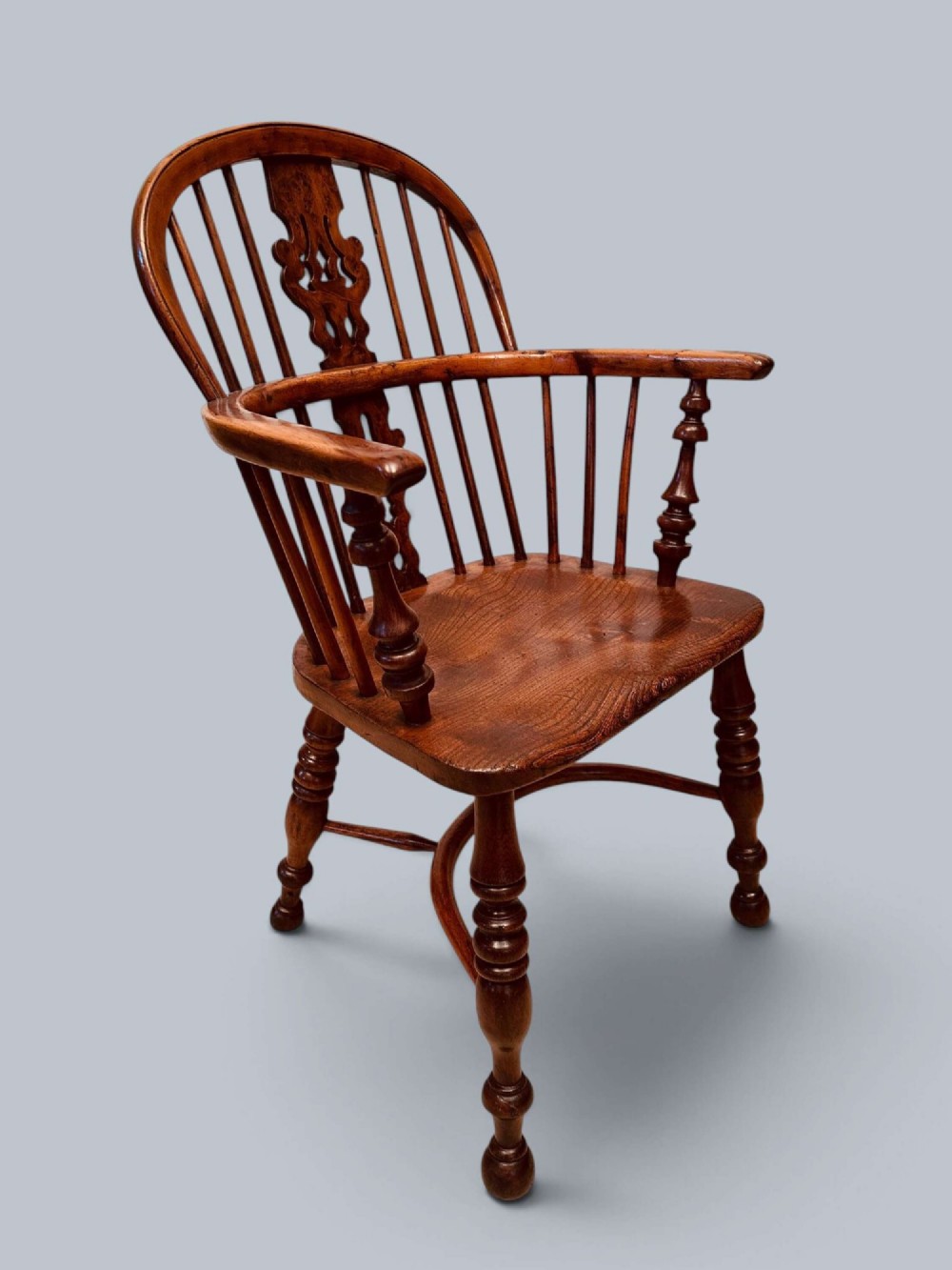 A pair of 19th-century yew wood Windsor armchairs featuring low hoop backs, pierced central splats, turned spindle supports, and shaped seats. View III
