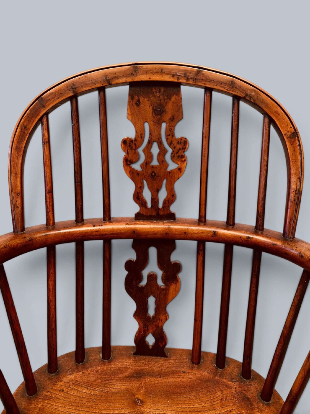 A pair of 19th-century yew wood Windsor armchairs featuring low hoop backs, pierced central splats, turned spindle supports, and shaped seats. View V