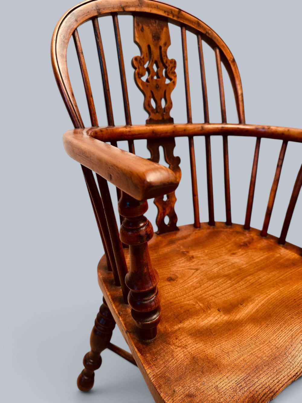 A pair of 19th-century yew wood Windsor armchairs featuring low hoop backs, pierced central splats, turned spindle supports, and shaped seats. View VI