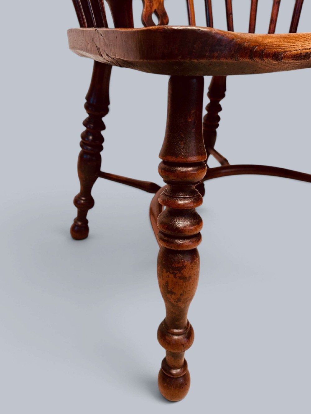A pair of 19th-century yew wood Windsor armchairs featuring low hoop backs, pierced central splats, turned spindle supports, and shaped seats. View VII