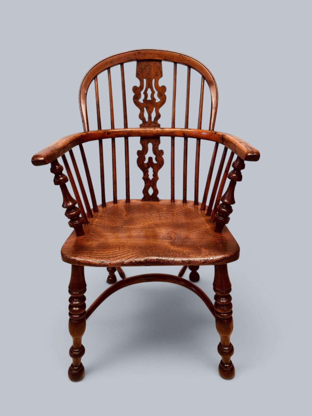A pair of 19th-century yew wood Windsor armchairs featuring low hoop backs, pierced central splats, turned spindle supports, and shaped seats. View IX