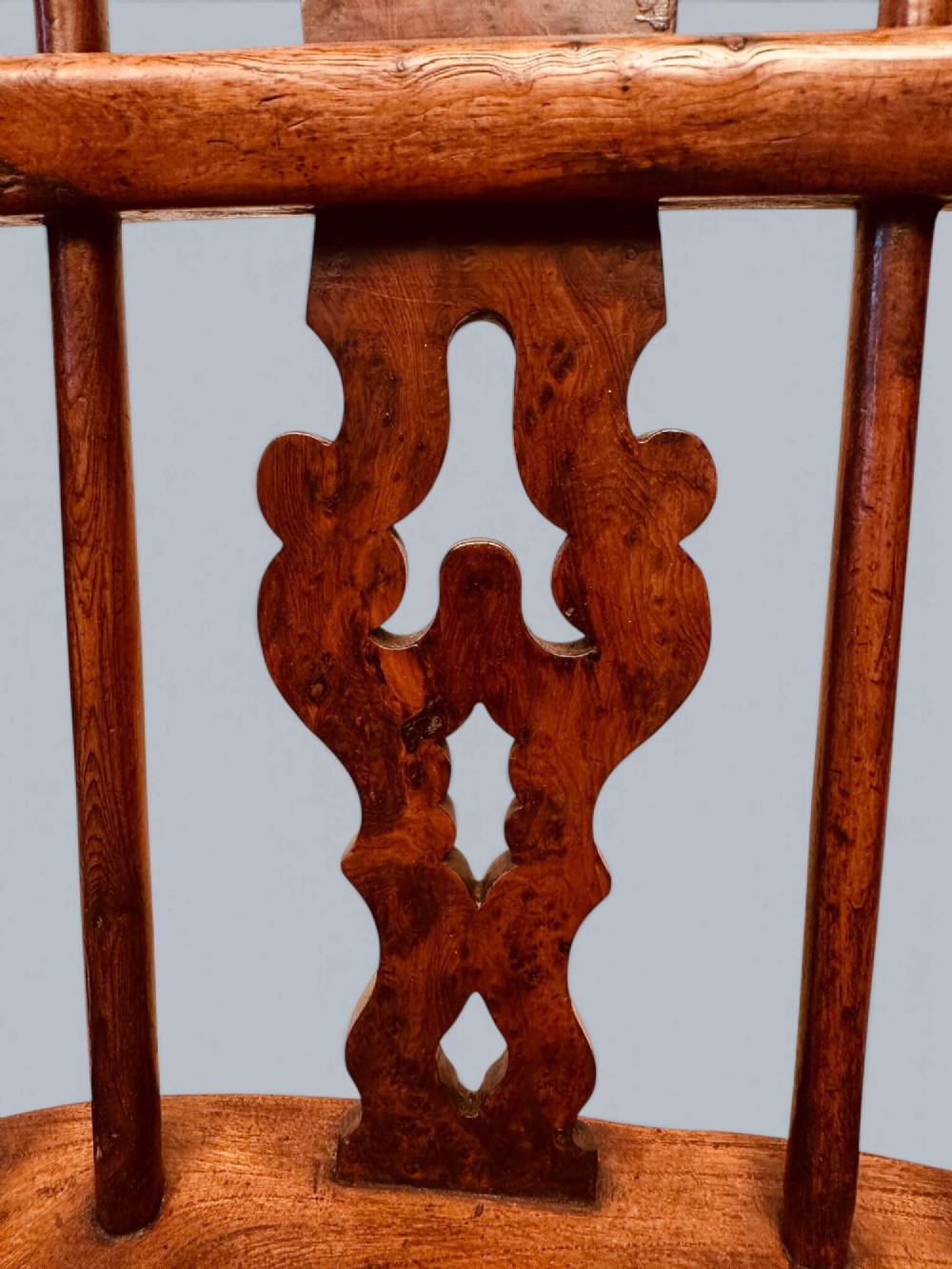 A pair of 19th-century yew wood Windsor armchairs featuring low hoop backs, pierced central splats, turned spindle supports, and shaped seats. View X