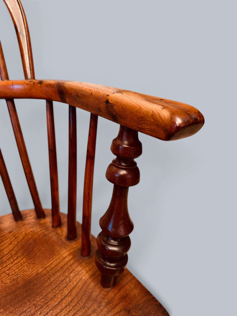 A pair of 19th-century yew wood Windsor armchairs featuring low hoop backs, pierced central splats, turned spindle supports, and shaped seats. View XI