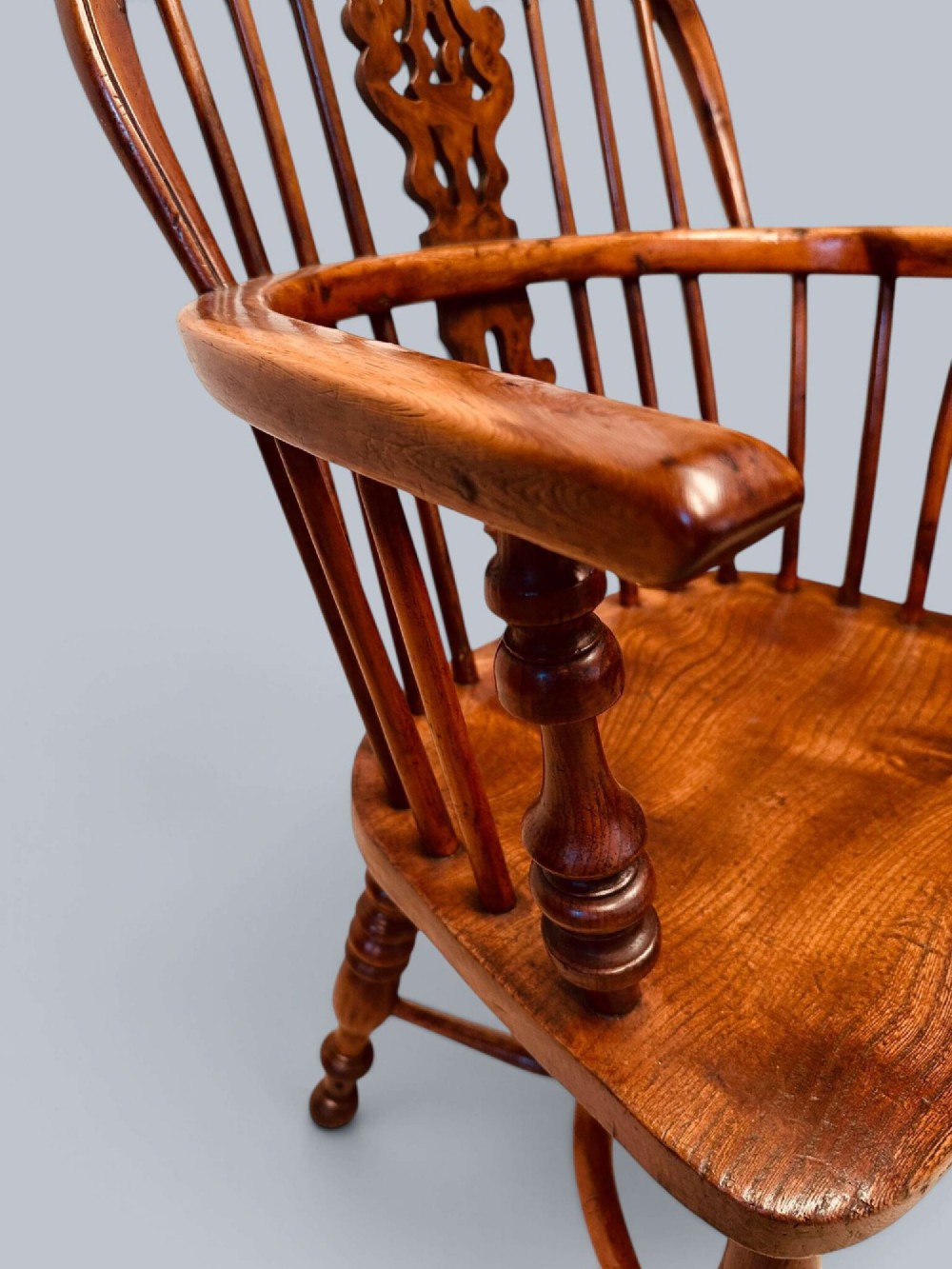 A pair of 19th-century yew wood Windsor armchairs featuring low hoop backs, pierced central splats, turned spindle supports, and shaped seats. View XII