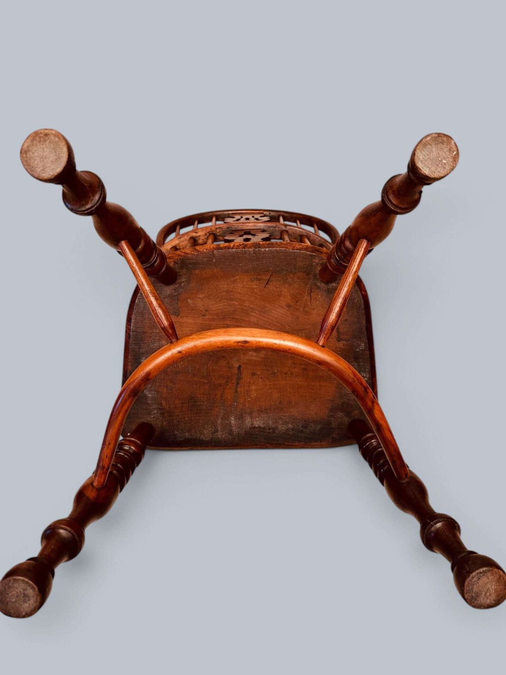 A pair of 19th-century yew wood Windsor armchairs featuring low hoop backs, pierced central splats, turned spindle supports, and shaped seats. View XIV