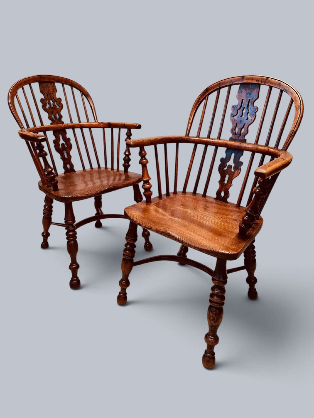 A pair of 19th-century yew wood Windsor armchairs featuring low hoop backs, pierced central splats, turned spindle supports, and shaped seats. View XV