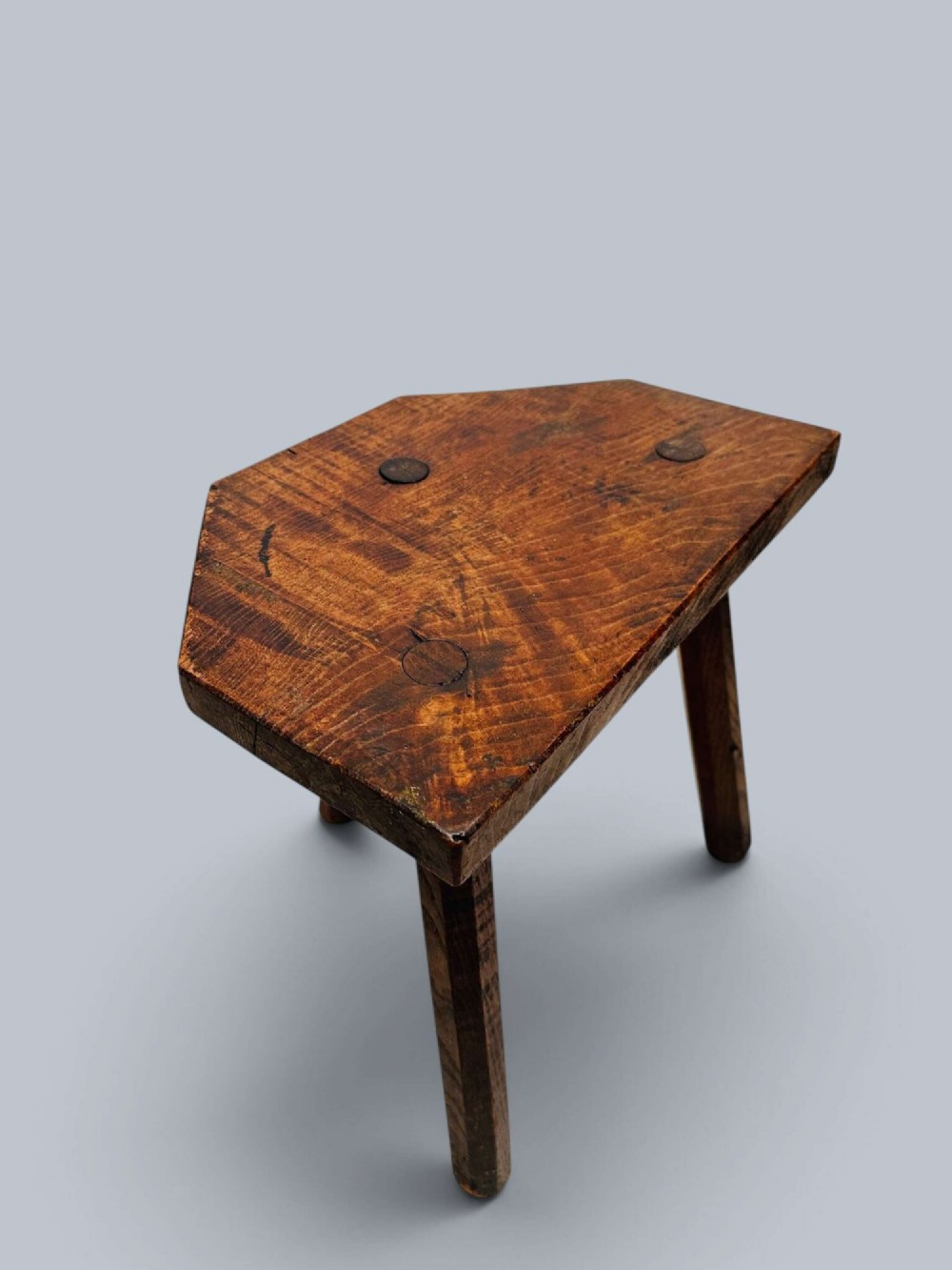 A rustic nineteenth-century three-legged wooden stool with a shaped elm seat and wedged tenon joinery visible on the top. View II