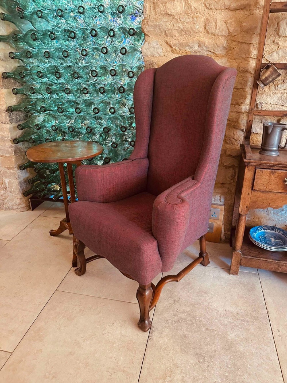 A high-backed Queen Anne style wing armchair upholstered in burgundy textured fabric with walnut cabriole front legs and curved stretchers.
