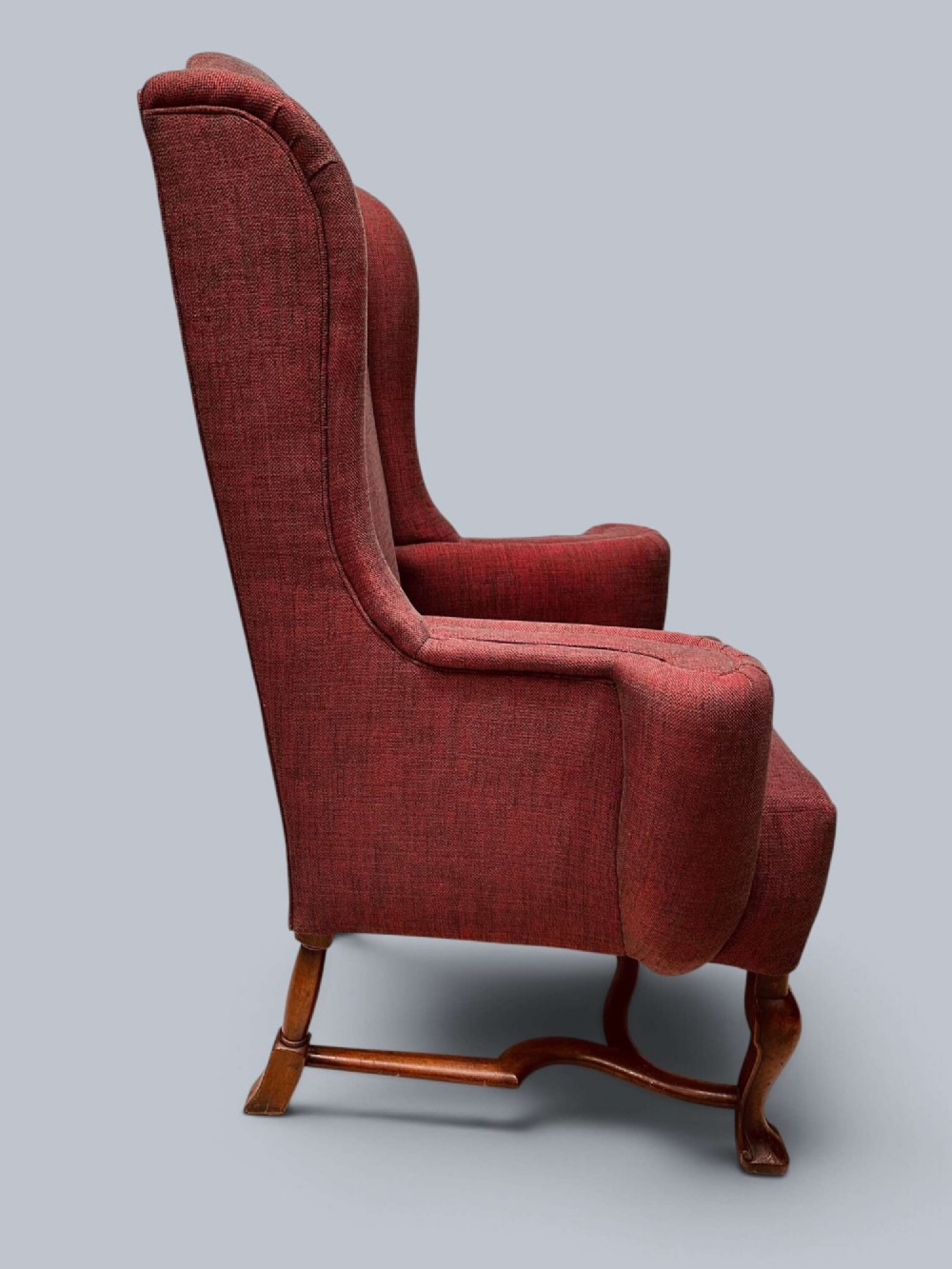A high-backed Queen Anne style wing armchair upholstered in burgundy textured fabric with walnut cabriole front legs and curved stretchers. View IV