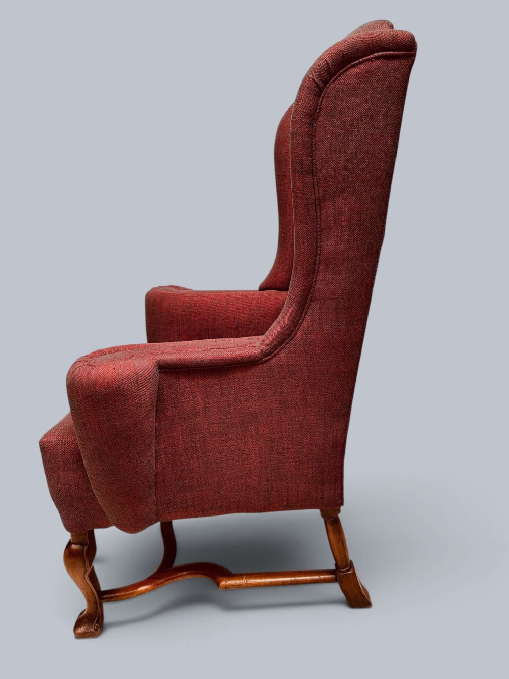 A high-backed Queen Anne style wing armchair upholstered in burgundy textured fabric with walnut cabriole front legs and curved stretchers. View V