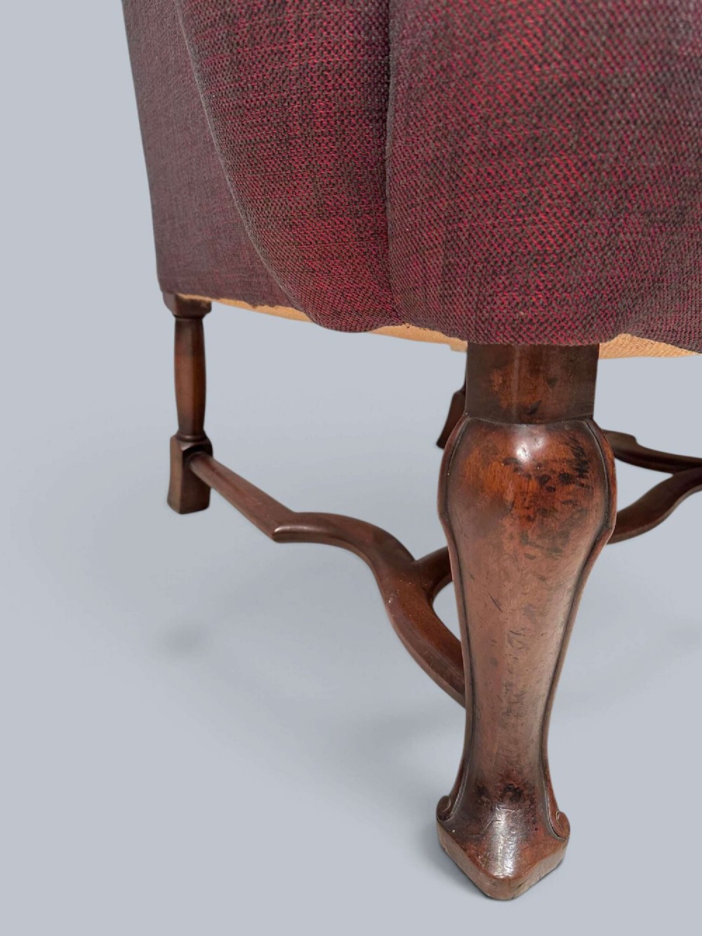 A high-backed Queen Anne style wing armchair upholstered in burgundy textured fabric with walnut cabriole front legs and curved stretchers. View VII