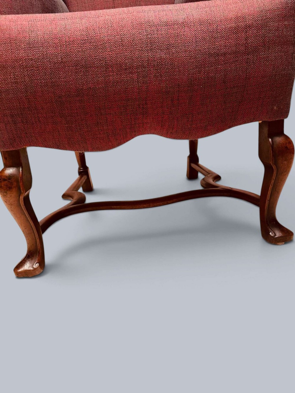 A high-backed Queen Anne style wing armchair upholstered in burgundy textured fabric with walnut cabriole front legs and curved stretchers. View VIII