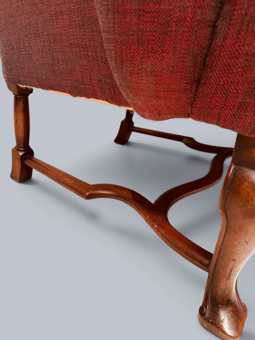 A high-backed Queen Anne style wing armchair upholstered in burgundy textured fabric with walnut cabriole front legs and curved stretchers. View IX