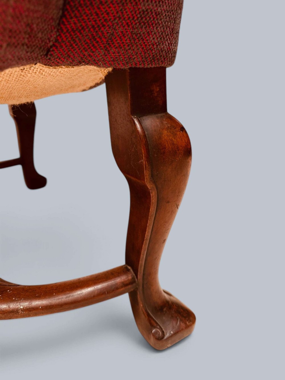 A high-backed Queen Anne style wing armchair upholstered in burgundy textured fabric with walnut cabriole front legs and curved stretchers. View XI