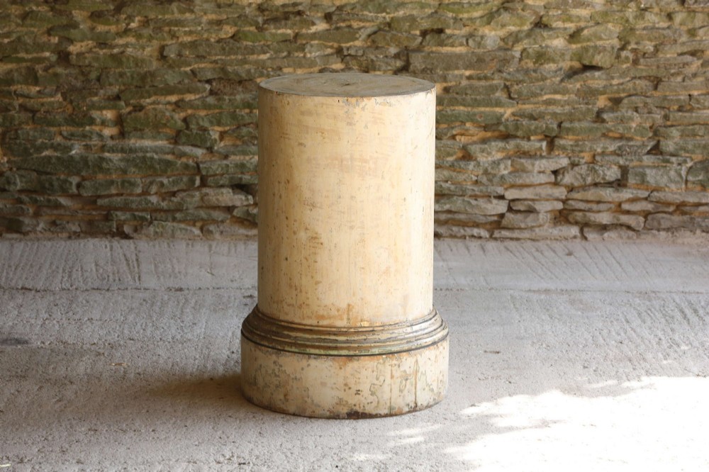 A cylindrical 18th-century Neoclassical painted pine column pedestal with a stepped moulded base and a weathered cream paint finish.
