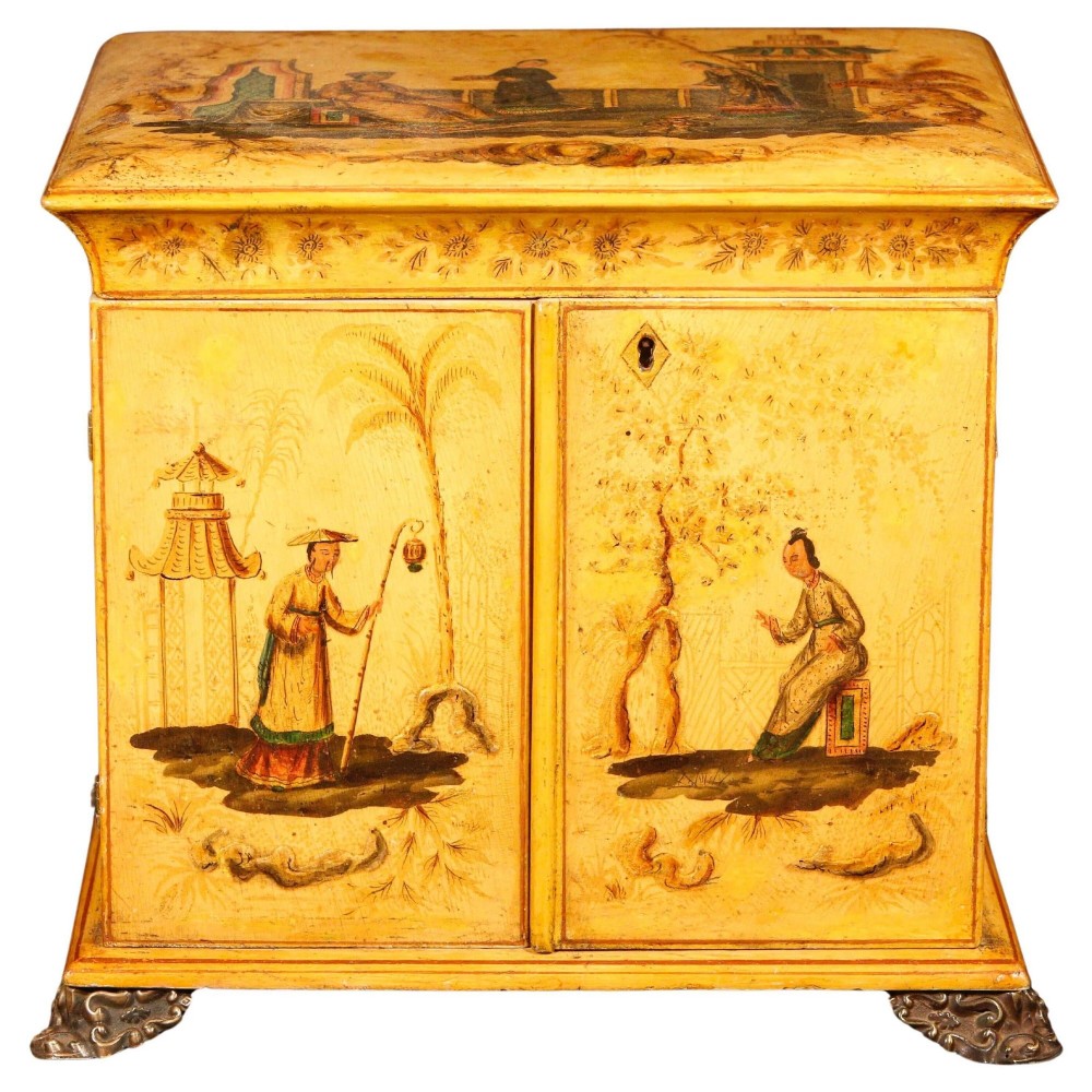 A yellow japanned Regency table cabinet decorated with hand-painted Chinoiserie figures and architecture, elevated on ornate metal feet.