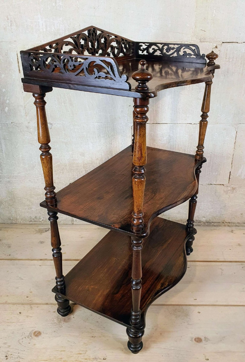 A three-tiered Victorian rosewood whatnot featuring turned spindle supports, serpentine-fronted shelves, and a decorative pierced fretwork top gallery. View III