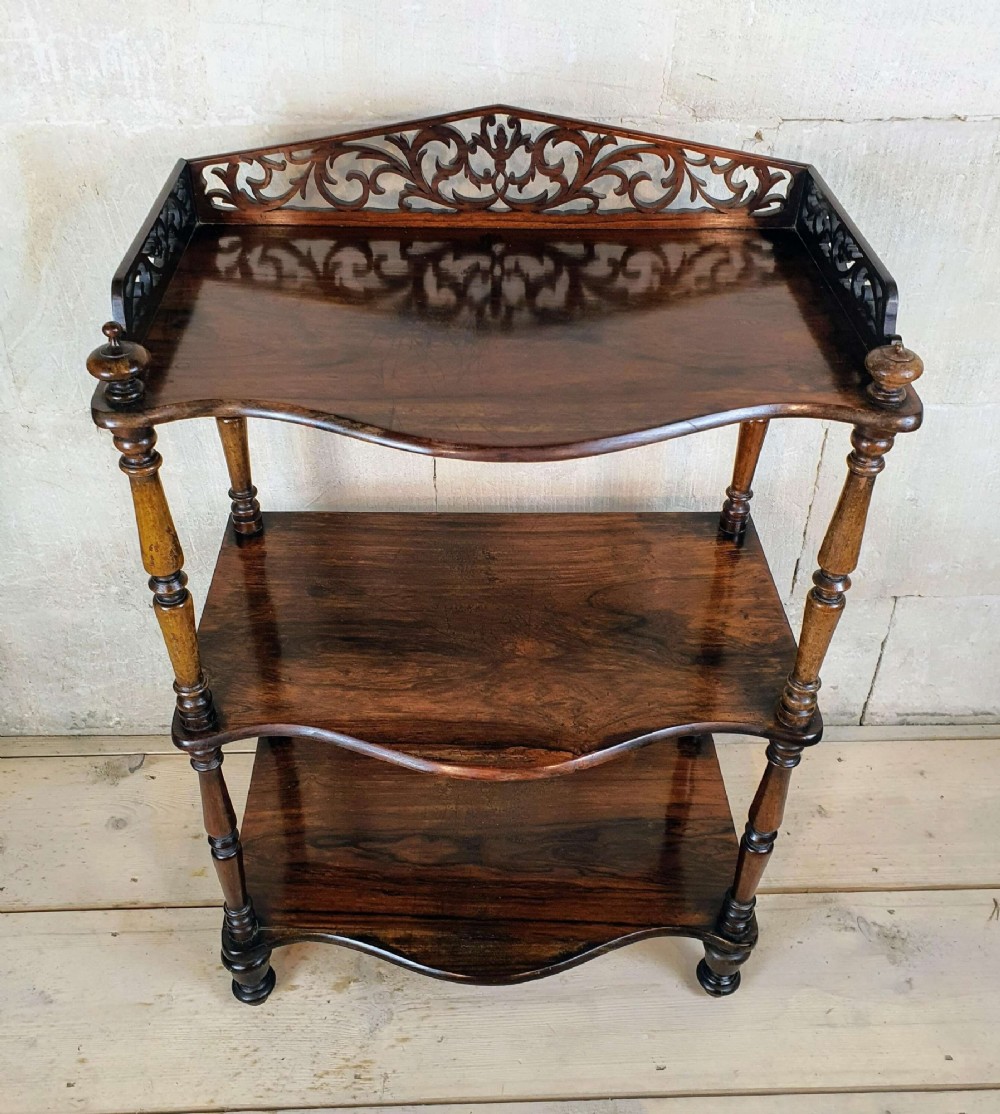 A three-tiered Victorian rosewood whatnot featuring turned spindle supports, serpentine-fronted shelves, and a decorative pierced fretwork top gallery. View IX