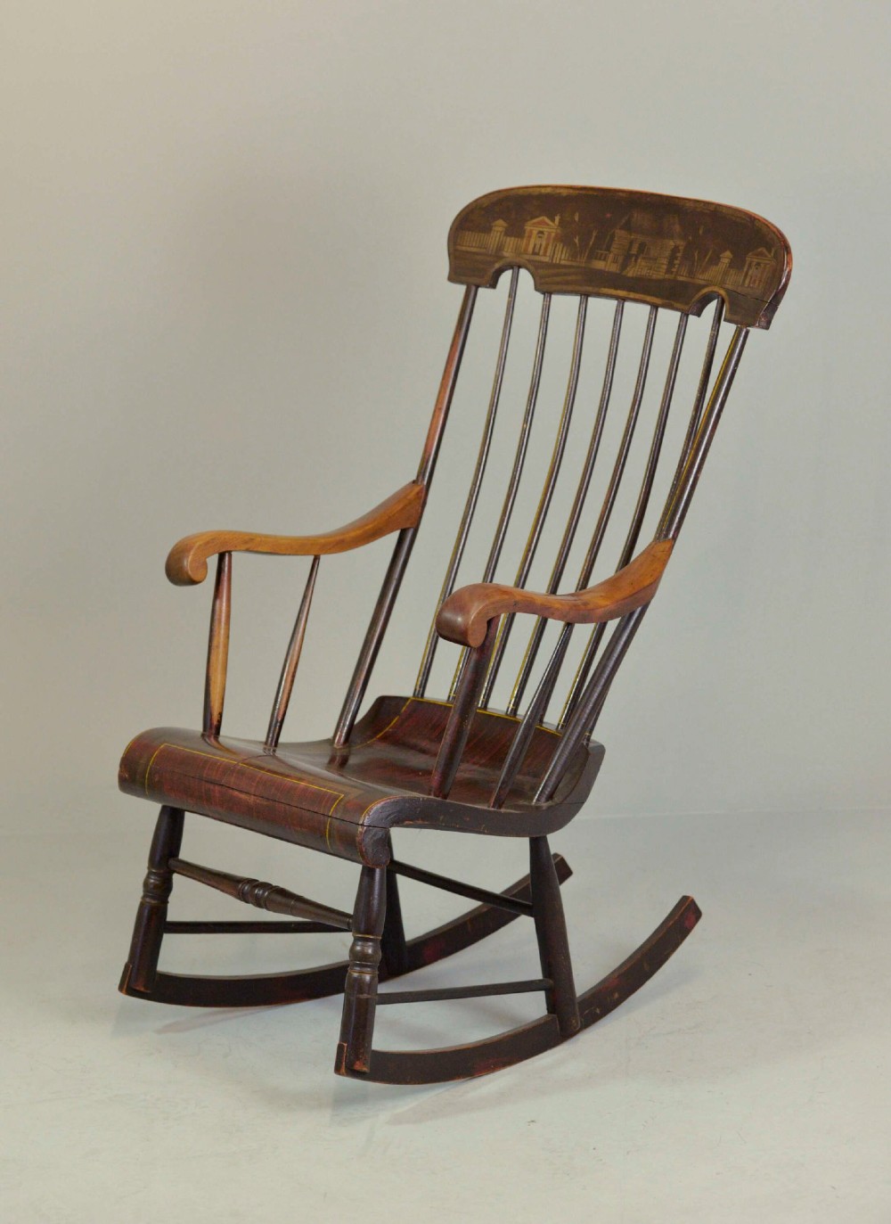 An antique American Boston rocking chair crafted from dark painted timber with a tall spindle back, scrolled arms, a sculpted seat, and a painted landscape motif across the top crest.