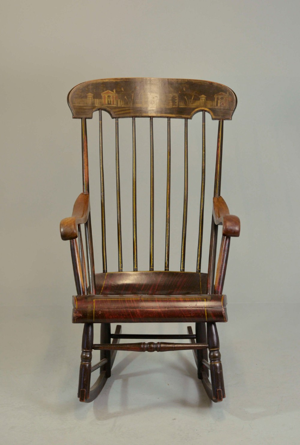 An antique American Boston rocking chair crafted from dark painted timber with a tall spindle back, scrolled arms, a sculpted seat, and a painted landscape motif across the top crest. View II
