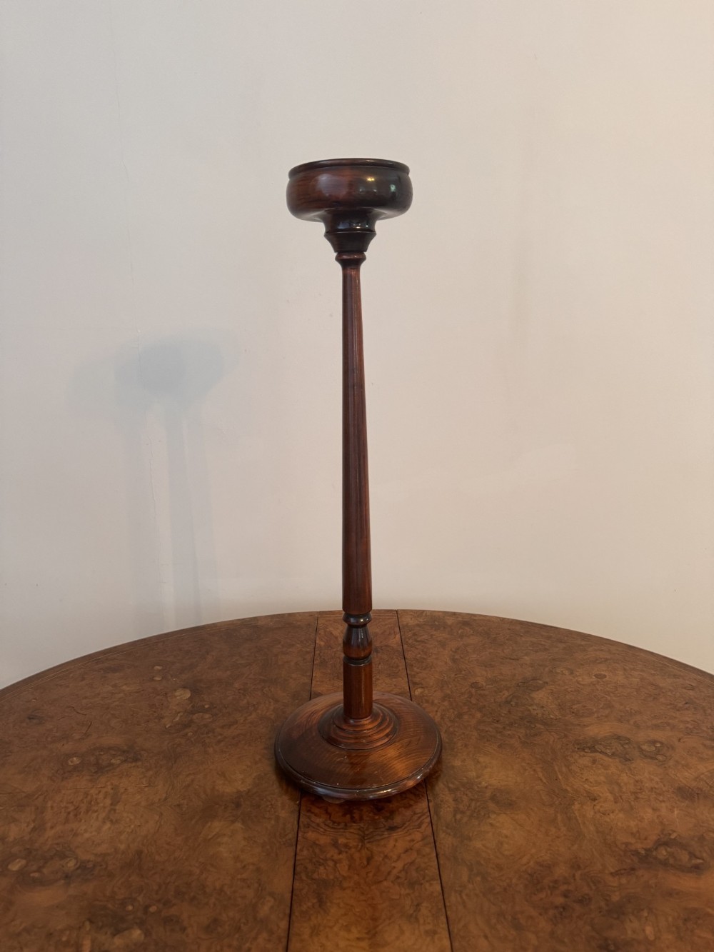 An antique dark mahogany smokers stand featuring a circular recessed top bowl set upon a slender turned stem and a heavy round base.