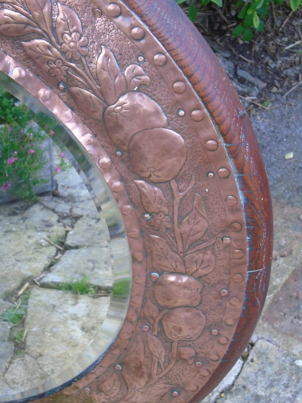 A circular antique Arts and Crafts copper wall mirror featuring hand-hammered repousse decoration of birds, foliage, and urns with a riveted border. View IV