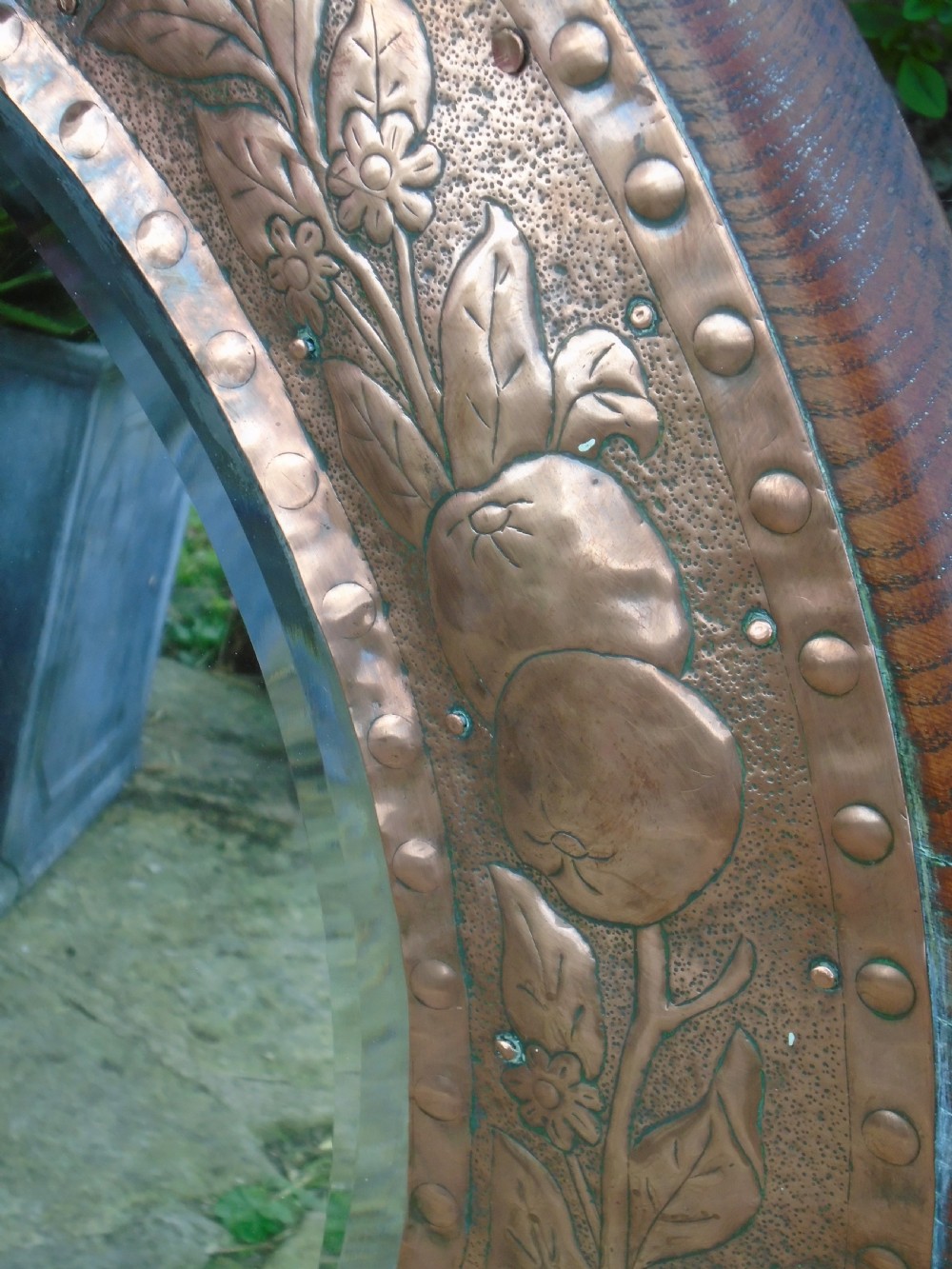 A circular antique Arts and Crafts copper wall mirror featuring hand-hammered repousse decoration of birds, foliage, and urns with a riveted border. View IX